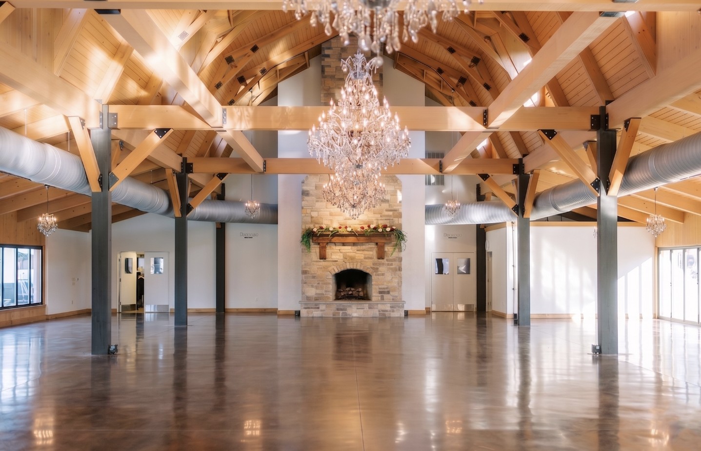 The empty reception hall with timber beams, chandeliers and a stone fireplace