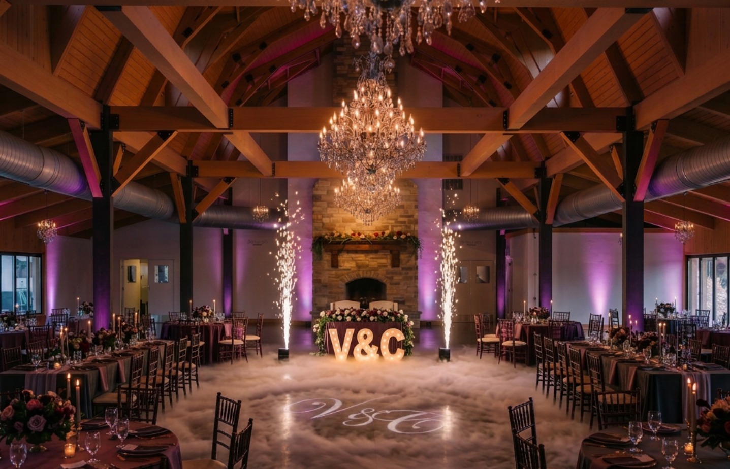 The same reception hall transformed with tables, uplighting, cold sparks, a cloud-covered dance floor and a monogram projection